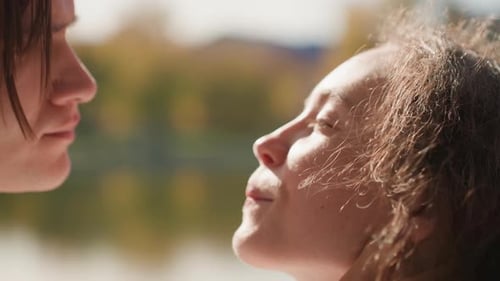 Young Couple Shares Quiet Moment Outdoors Couple Gazes Tenderly Beside Tranquil Lake Water Intimate
