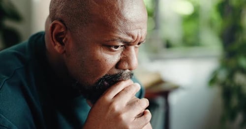 Man with beard looking thoughtful in home setting
