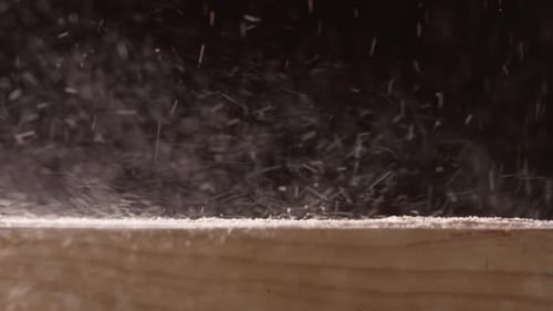 Blowing Sawdust On Wooden Surface Against Black Backdrop. Close Up