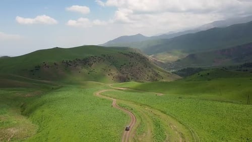 Drone: flies behind a car along the valley of the mountains of Kyrgyzstan