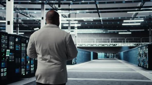 Technician Walking in Data Center Workplace with Rows of Mainframes