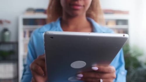 Woman Scrolls on Tablet Indoors in Close Up