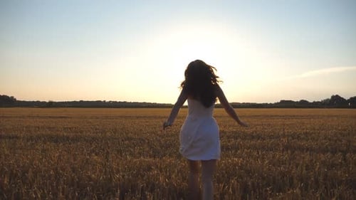 Beautiful Girl is Running Along Wheat Field at Sunset Young Woman Jogging at the Meadow and Enjoing