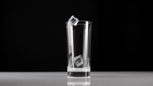 Ice Cubes Falling into Clear Glass