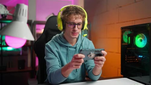 Young Adult Gaming on Mobile Device with Headphones