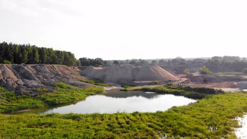 Drone dolly shot of dunes, pits and a pond in a quarry (pomorskie, Poland), showing contrast between