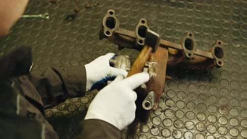Worker disassembles for repair old rusty car turbine turbocharger using hammer