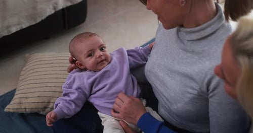 Happy female gay couple having tender moment with their baby son at home