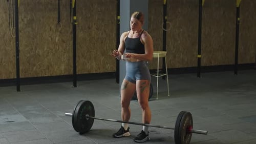 Woman prepares for weightlifting set at gym location in the early morning