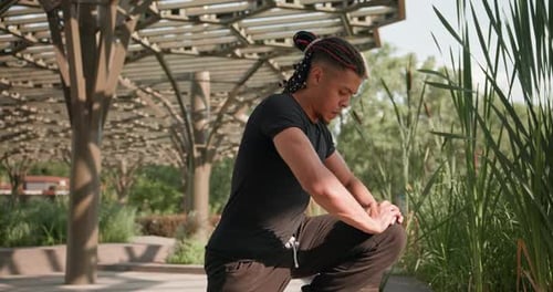 Man Stretching Leg in Urban Park on Sunny Day