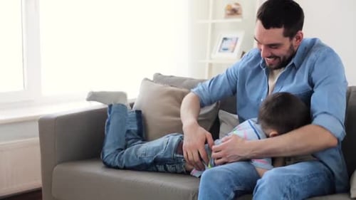 Father and Son Playfully Tickling on Couch