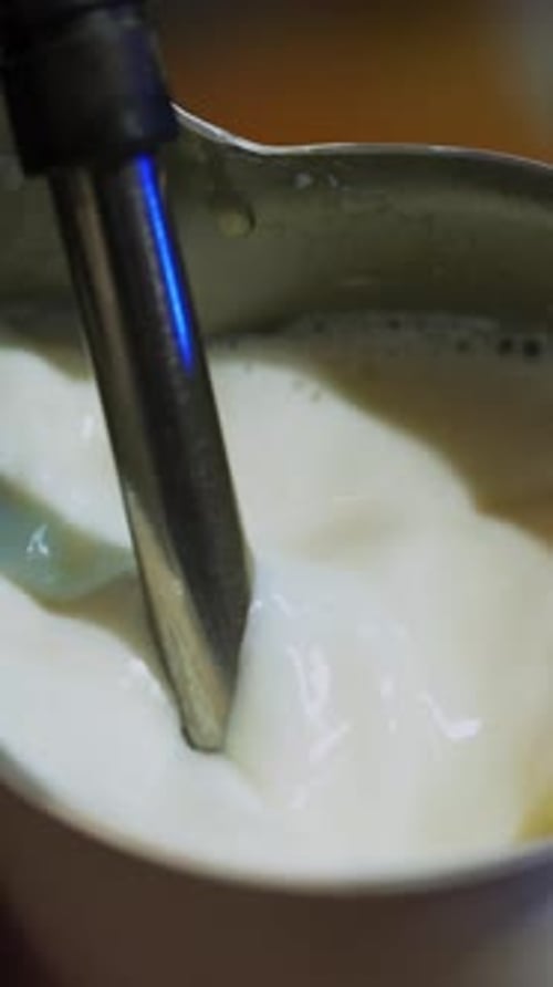 Hot milk pouring from coffee machine. Making fresh coffee with milk.