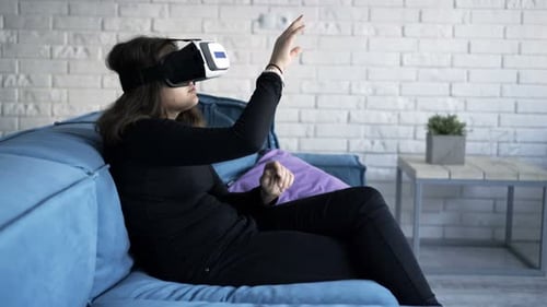 Teenage girl using virtual reality headset on couch