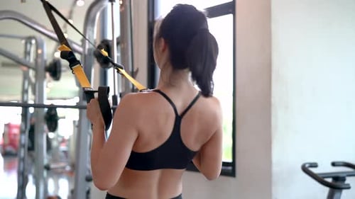 Fitness asian woman workout exercise with trx equipment in the fitness gym