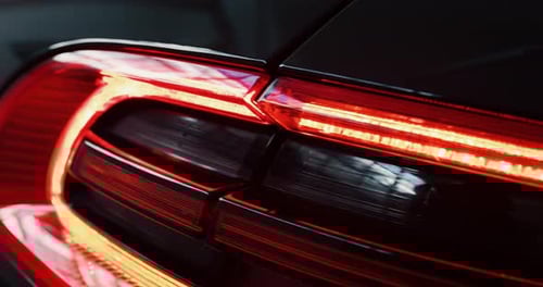 Close up of details of switched on tail lights of anonymous prestigious luxury modern car. Shot in