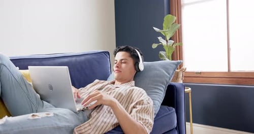 Young Adult Lying on Couch Using Laptop