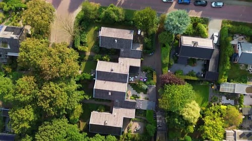 Aerial view of a planned residential neighborhood with dark-roofed houses, gardens, patios