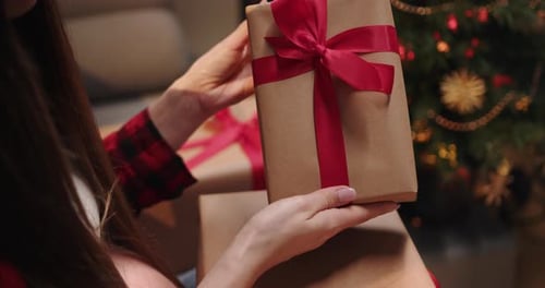 Woman Inspecting Christmas Present Wrapped in Brown Paper
