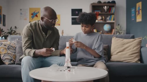 Little Kid and Father Building Rocket Model at Home