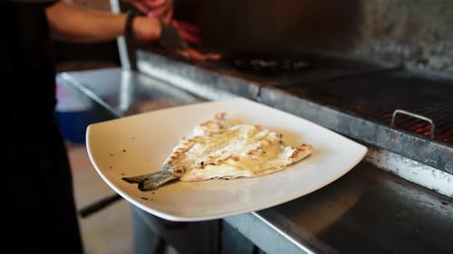 Chef Putting The Cooked Fish From The Grill To The Dish
