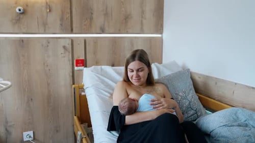Lady with newborn baby in nursery ward. Modern pregnant hospital room.