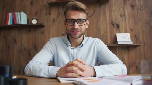 Young Man Explaining Concept at Desk with Books