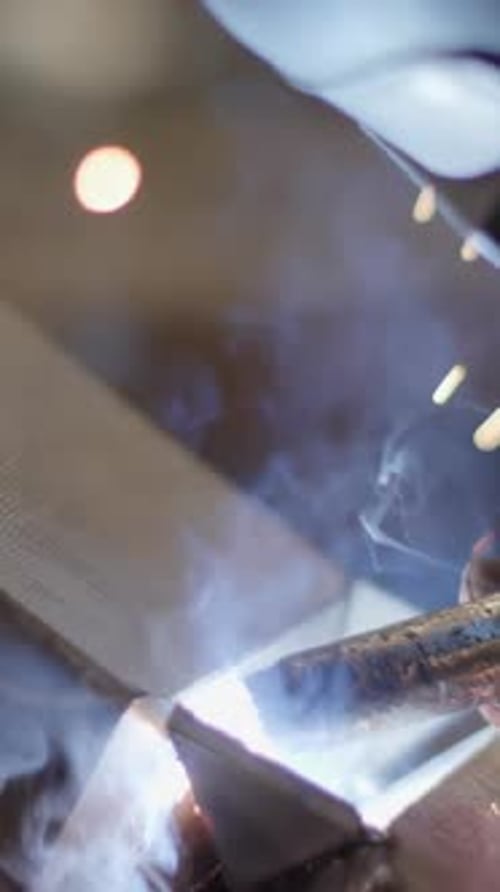 A Skilled Welder is in Action Creating with Beautiful Sparks and Smoke Effects During the Job Stock