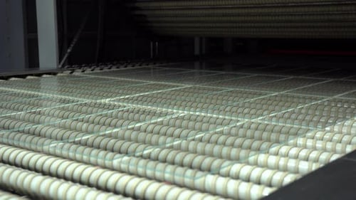 Unzerbrechliches Glas. Verfahren aus gehärtetem Glas. Kleine Glasscheiben auf der Förderrolle führen zum Aushärten