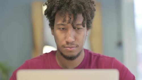Close Up of African Man Typing on Laptop in Office