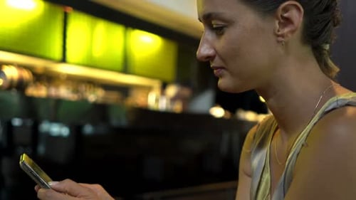 Young woman texting on smartphone enjoying coffee at a cafe in the city