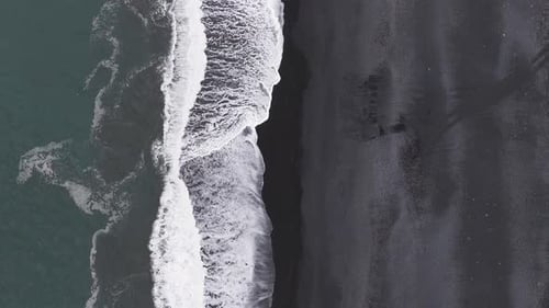 Aerial View of Iceland's Black Sand Beach with Crashing Waves