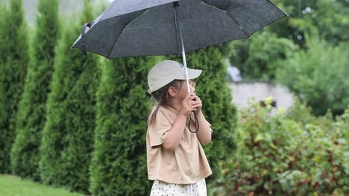 Little Girl Holding an Open Umbrella in Her Hands During the Rain