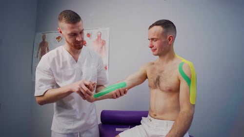 Kinesiology Physiotherapist Works Out the Hand of an Athlete with Kinesio Tape