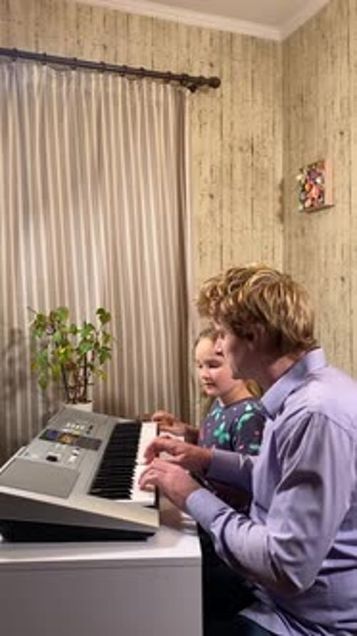Child Learning Piano with the Help of Young Adult