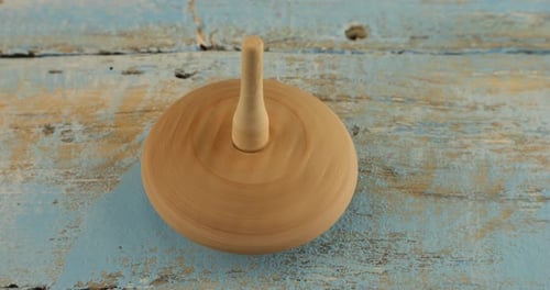 Wooden Spinning Top Rotating on Blue Surface