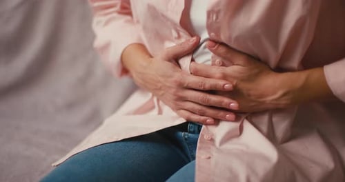 Adult With Hands on Stomach on Couch