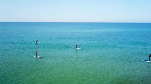 SUP surfers paddling along a Mediterranean coast