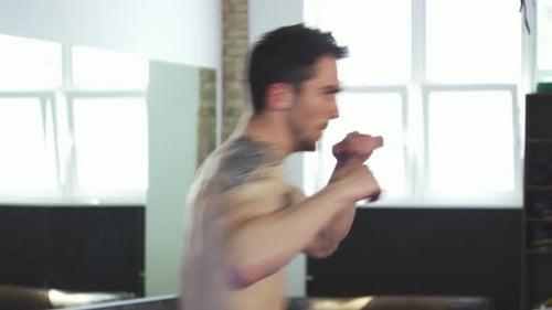Intense Muscular Male Boxer Shadow Boxing in a Bright Gym