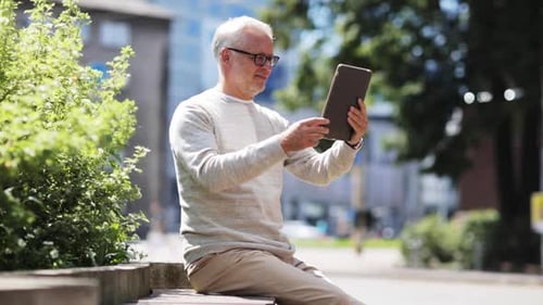 Senior man using tablet on park bench
