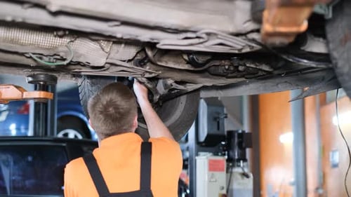 An American Auto Mechanic Inspects a Car While Working in an Auto Repair Shop
