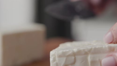Gros plan des mains coupant un bloc de fromage feta avec un gros