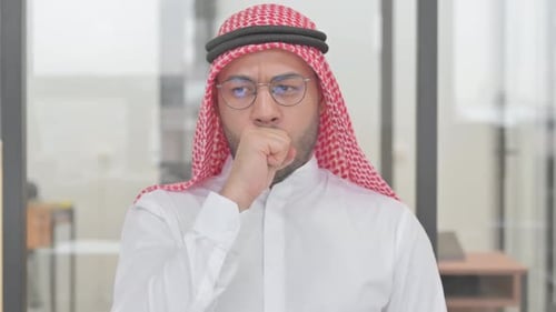 Man in head covering coughs into hand