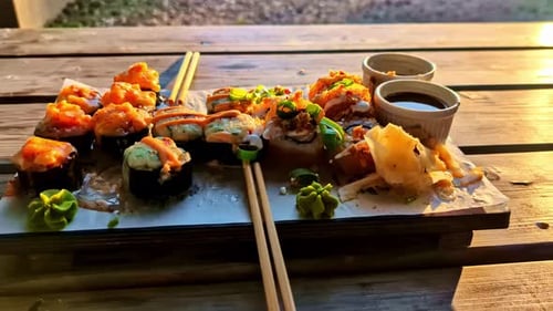 Platter Of Sushi With Dipping Sauces And Glass Of Refreshing Drink On The Side. - closeup shot