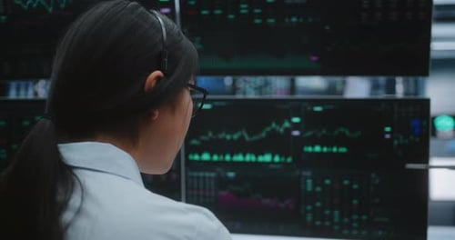 Female Specialist Tracks Market Volatility on Large Screens in Massive Innovative Digital Office