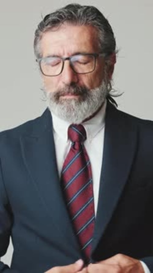 Man Buttoning Navy Suit Jacket and Adjusting Tie
