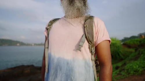Stylish Handsome Senior Man in Tshirt Shorts Backpack with Grey Beard Sunbathes and Enjoys View of