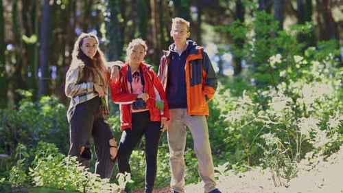 Tres personas están de pie en un bosque posando para una foto