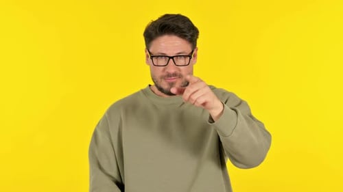Casual Young Man Pointing at Camera on Yellow Background, Portrait