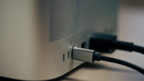 Hand plugs USB-C cable into desktop computer
