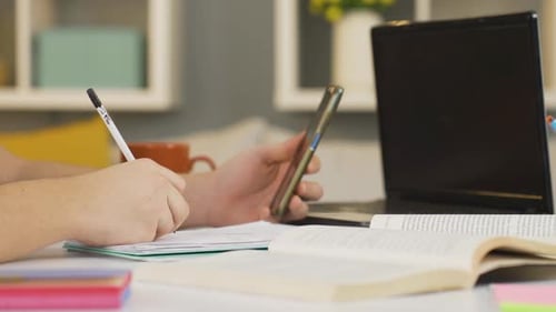 Student Studying with Laptop, Phone, Book, and Pencil